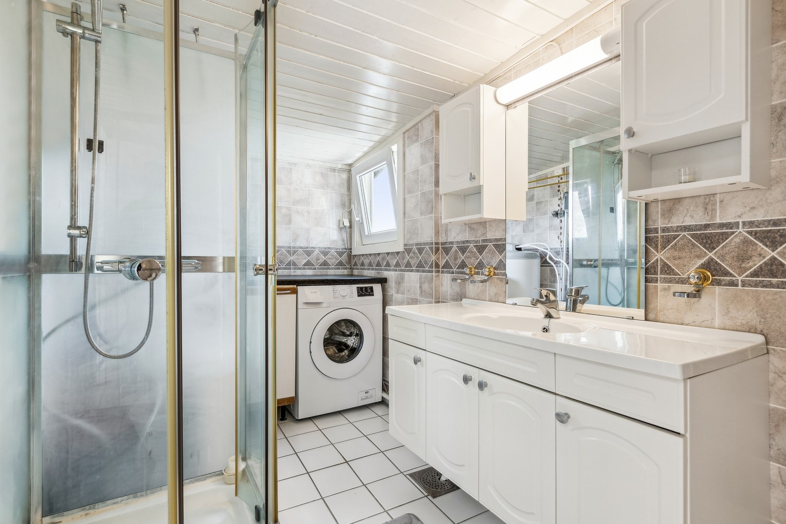 Badet er utstyrt med dusjkabinett, servant i baderomsinnredning, gulvmontert toalett og opplegg for vaskemaskin. Galleribilde