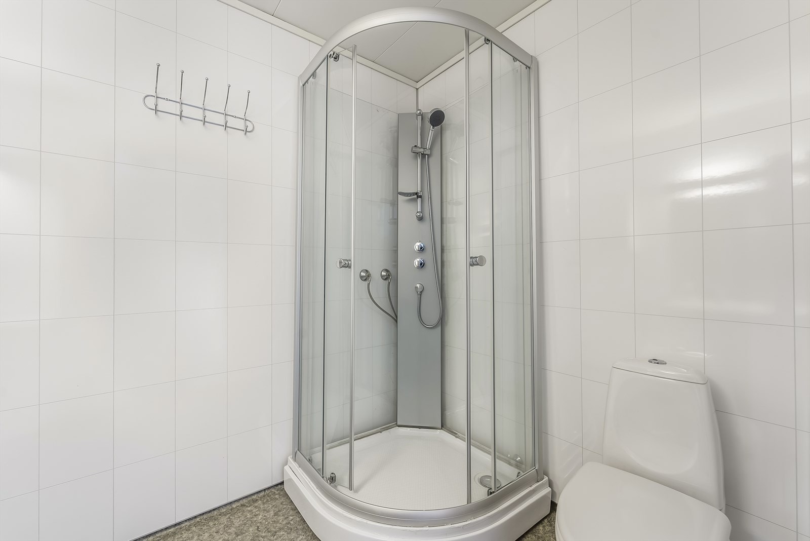 Pen bad med baderomsplater på vegg og belegg på gulv. Innredet med baderomsinnredning, toalett og dusjkabinett, samt opplegg til vaskemaskin. Galleribilde