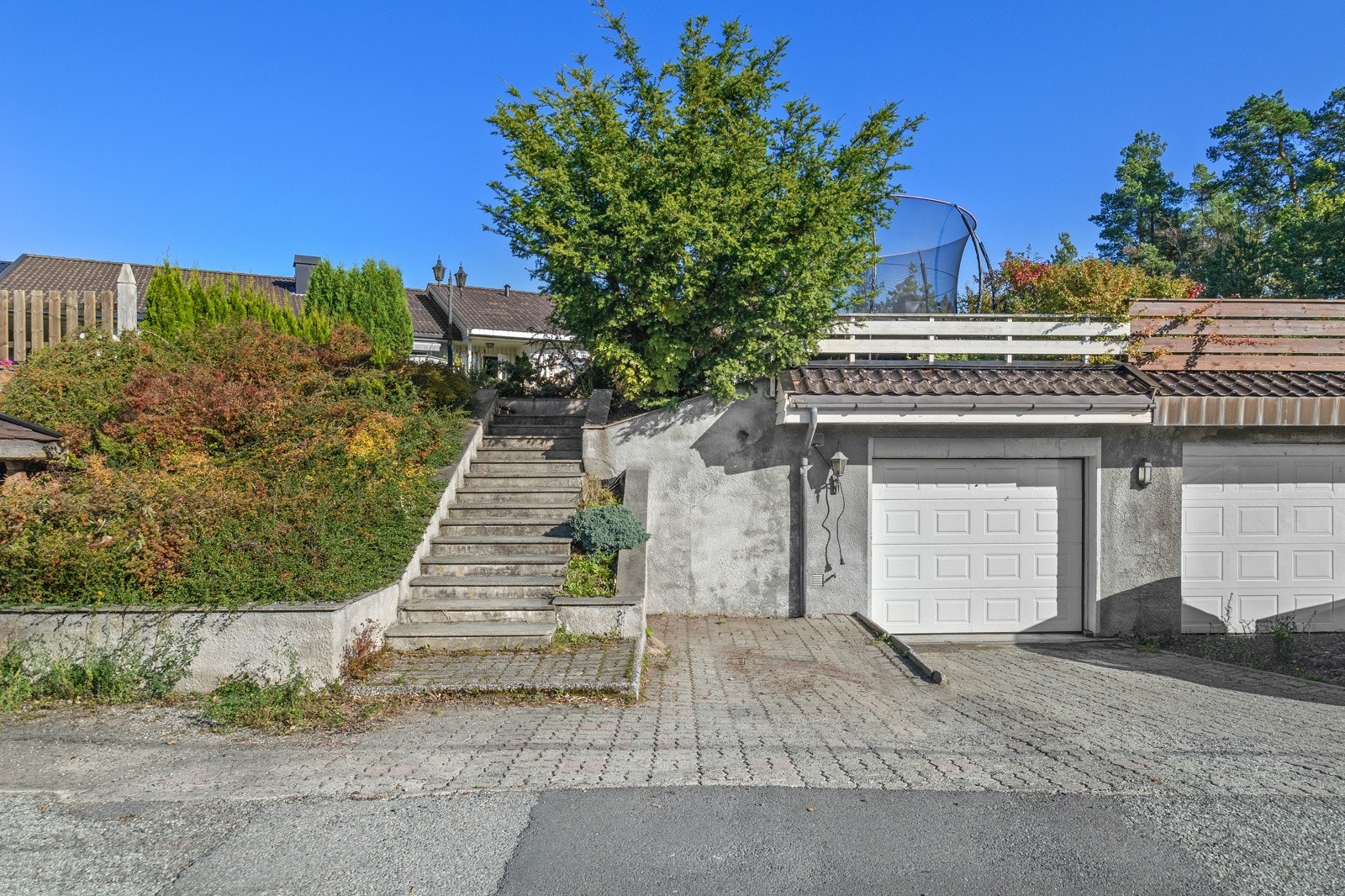 Eiendommen har garasje med plass til parkering og lagring i bod - Det er lagt varme i trappen opp til huset Galleribilde