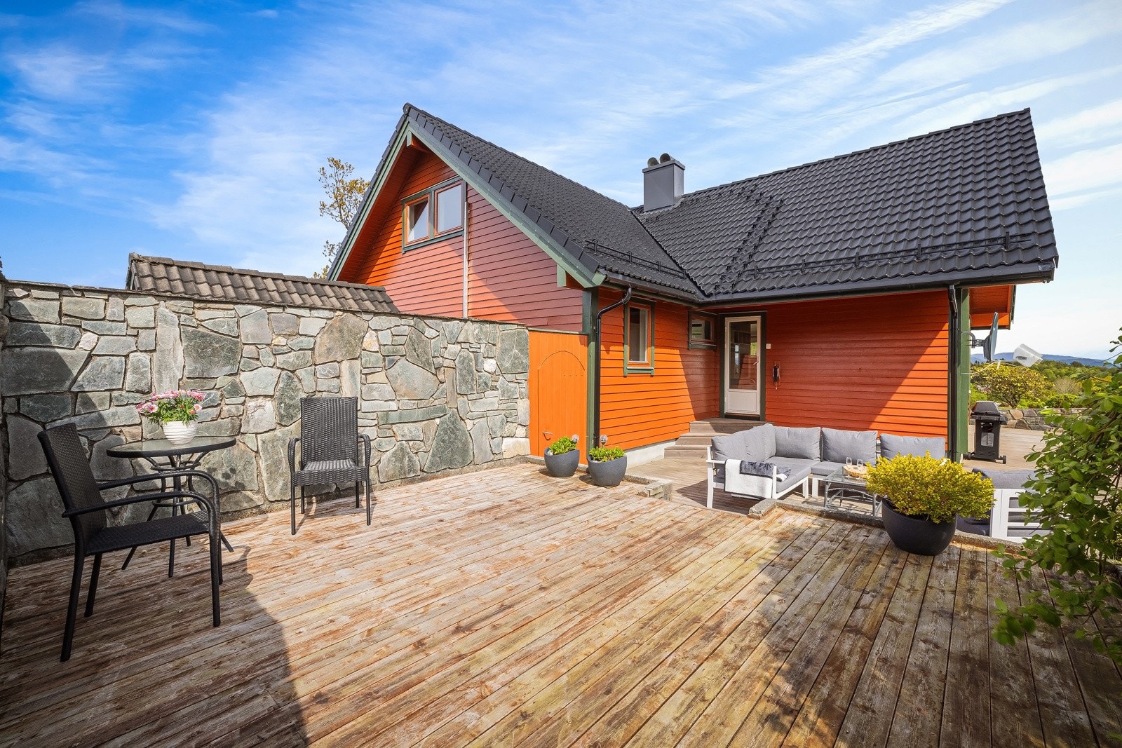 Stor terrasse over to plan på 100 kvm inndelt i ulike soner med flott levegg i naturstein Galleribilde