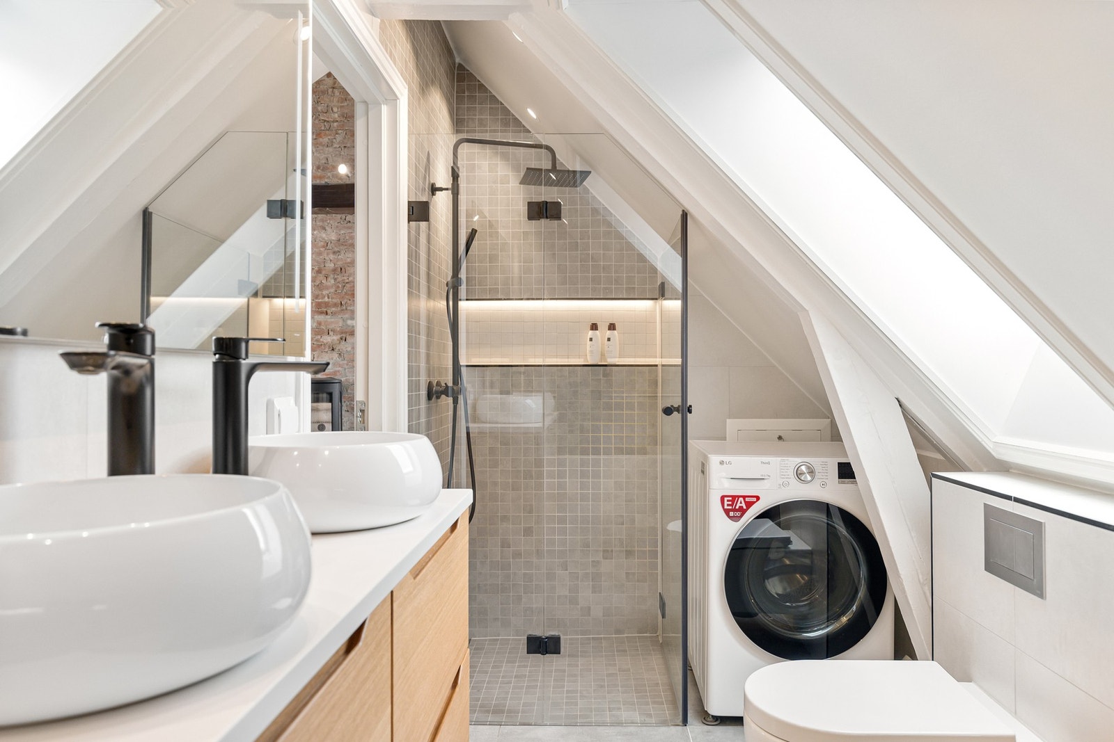 Badet er innredet med servantseksjon med doble servanter, speil med integrert belysning, dusjhjørne, badekar og vegghengt toalett. Galleribilde