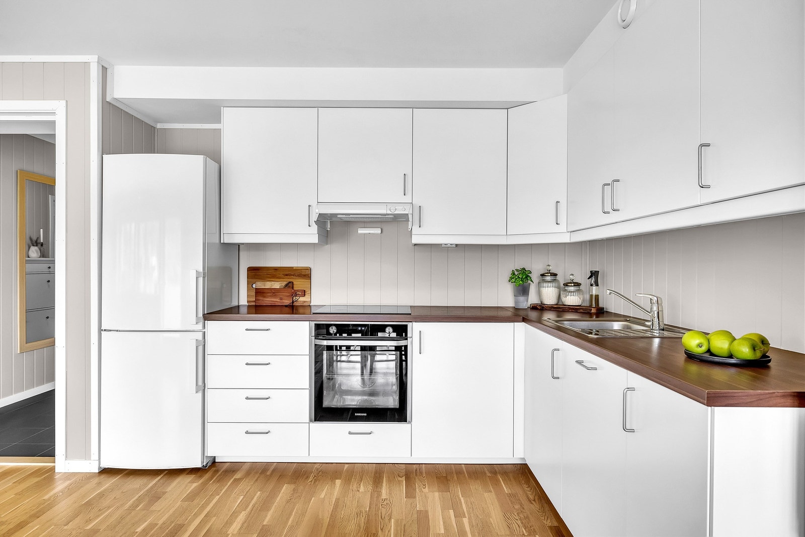 Hvit kjøkkeninnredning fra byggeår med glatte fronter og benkeplater av laminat. Galleribilde