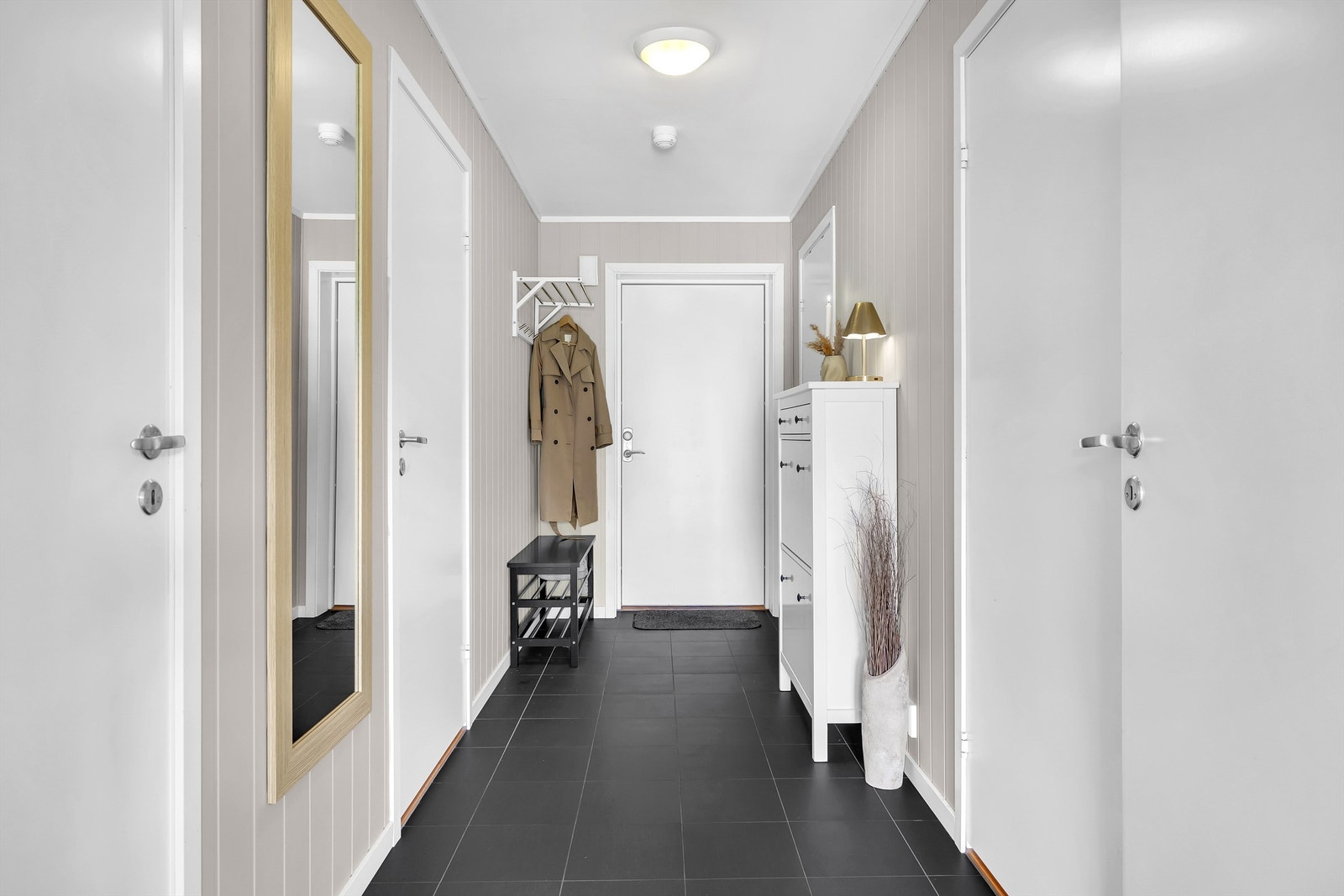 Du blir ønsket velkommen i en fin entré med sorte fliser på gulv med gulvvarme. Her er det godt med plass for å henge fra deg ytterklær og sko, samt mulighet for oppbevaring i ønskelig kommoder. Galleribilde