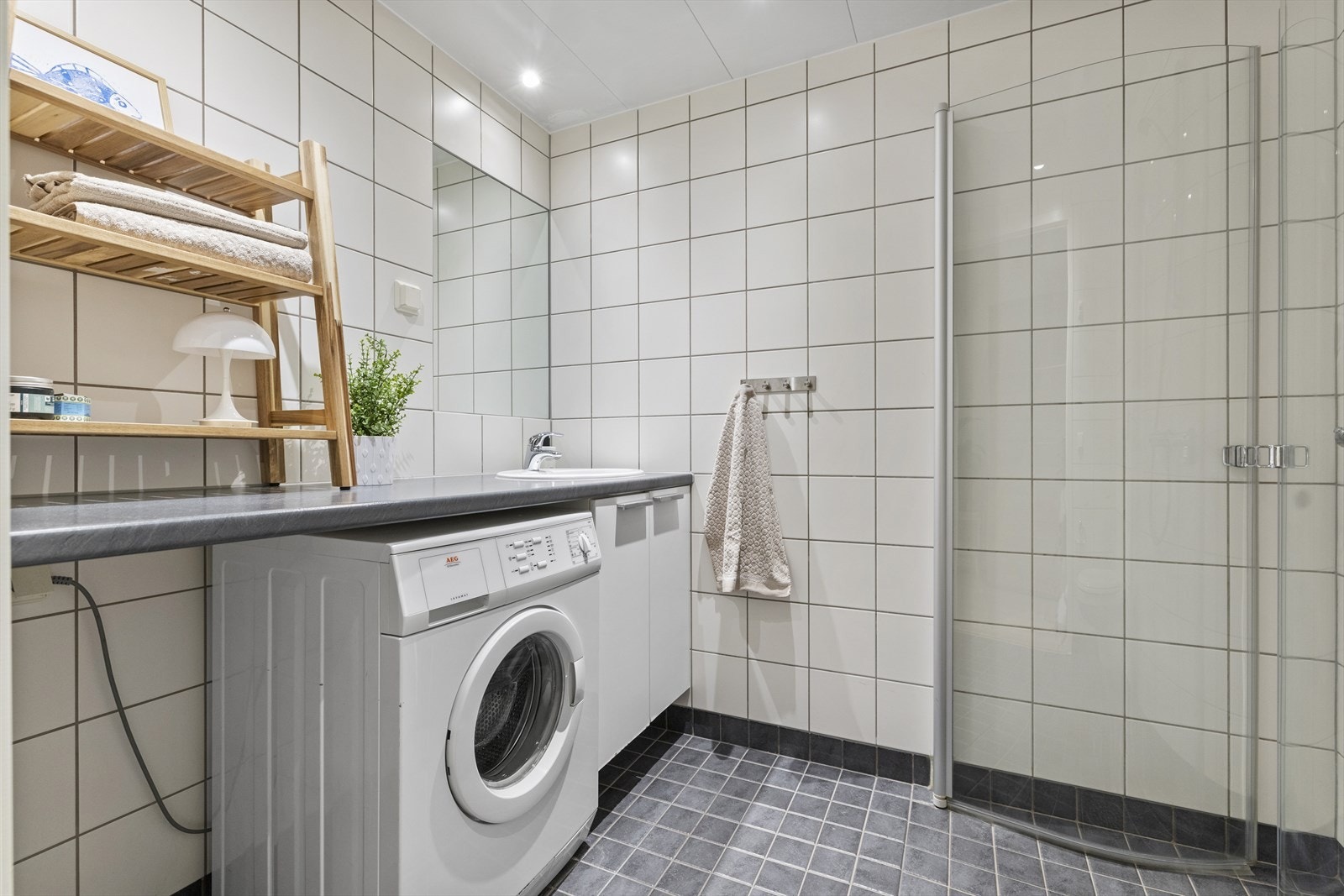 Flislagt tidsriktig baderom med lyse fliser på gulv og mørke kontrastfargede fliser på gulv. Opplegg til vaskemaskin. Vaskemaskin medfølger. Galleribilde