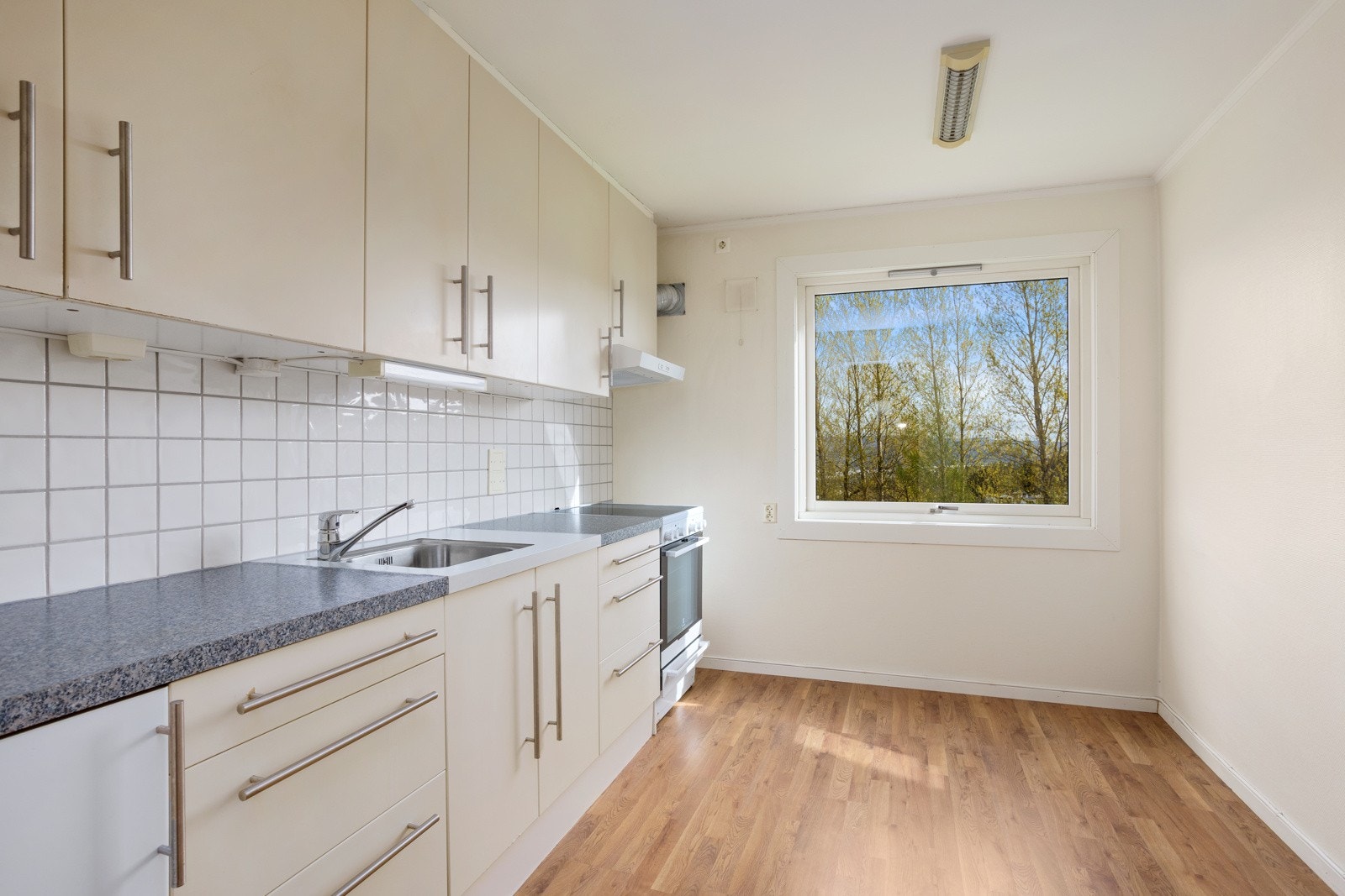 Lyst kjøkken med plass til spisebord foran vinduet. Galleribilde