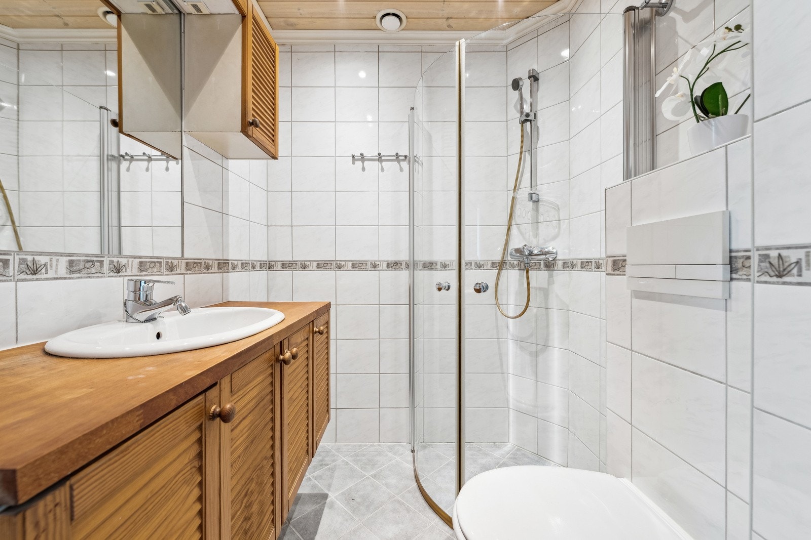 Bad/wc med gulvvarme, dusj og servant med tilhørende underskap og veggskap. Galleribilde