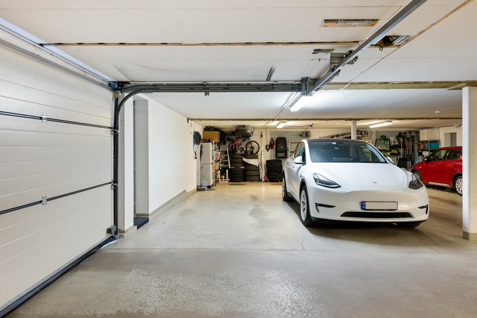 To garasjeplasser etter hverandre i kjeller med lader og egen sluse inn til boligen Galleribilde