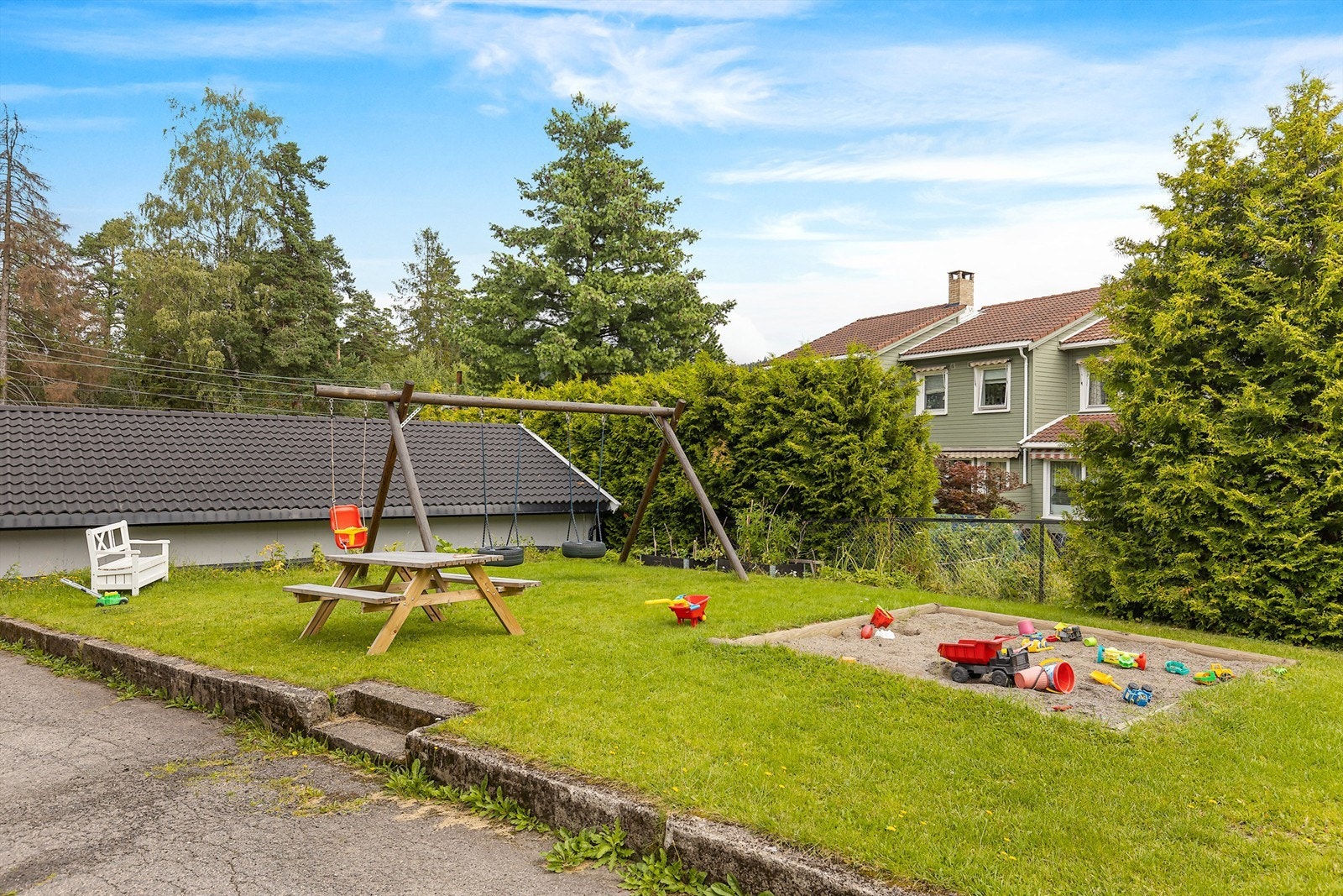 Sameiet har lekeplass med huskestativ, sandkasse og sittegrupper Galleribilde