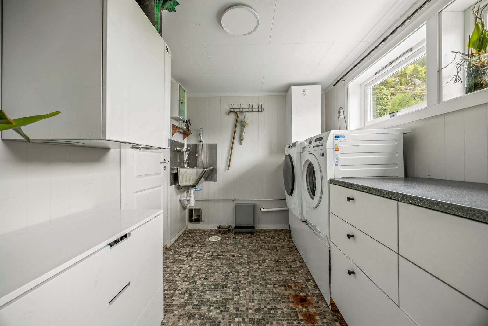 Praktisk vaskerom med gulvvarme. Her finner du oppleggg for vaskemaskin, skyllekum og benkeskap, samt ventilasjonsaggregat. Galleribilde