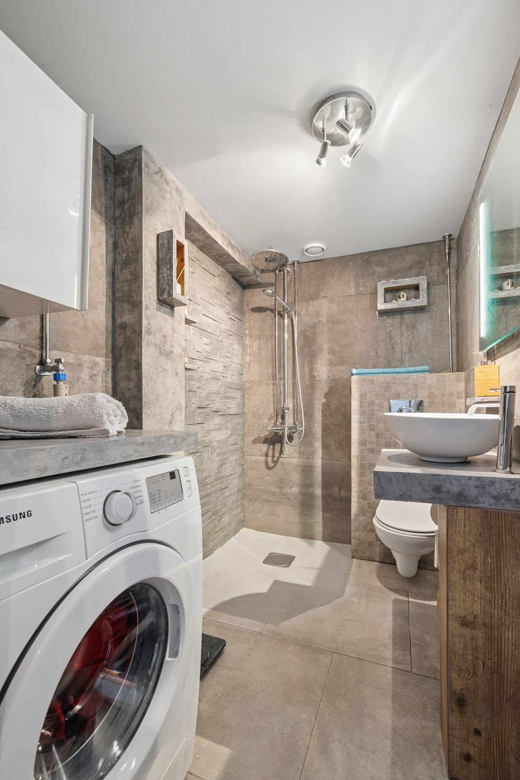 Det har flislagte vegger og gulv, elektriske varmekabler og mekanisk avtrekk, opplegg for vaskemaskin Galleribilde