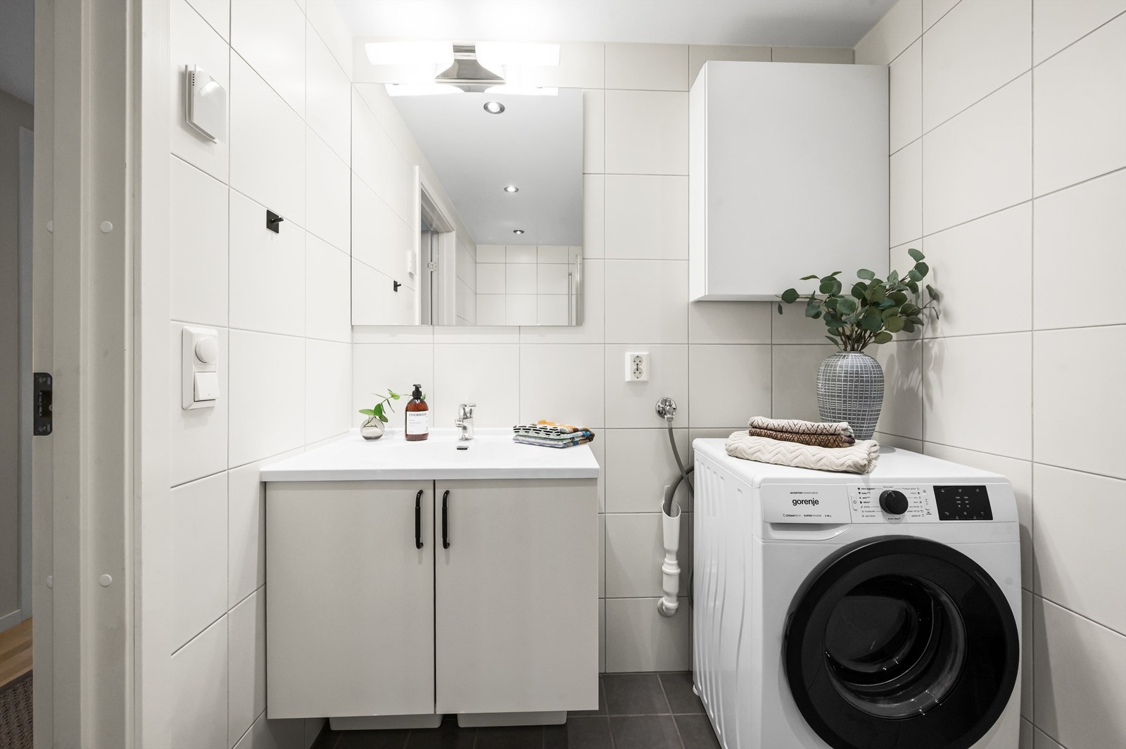 Videre har badet dusjhjørne med svingbare glassdører og vegghengt klosett. Det er opplegg for vaskemaskin. Galleribilde