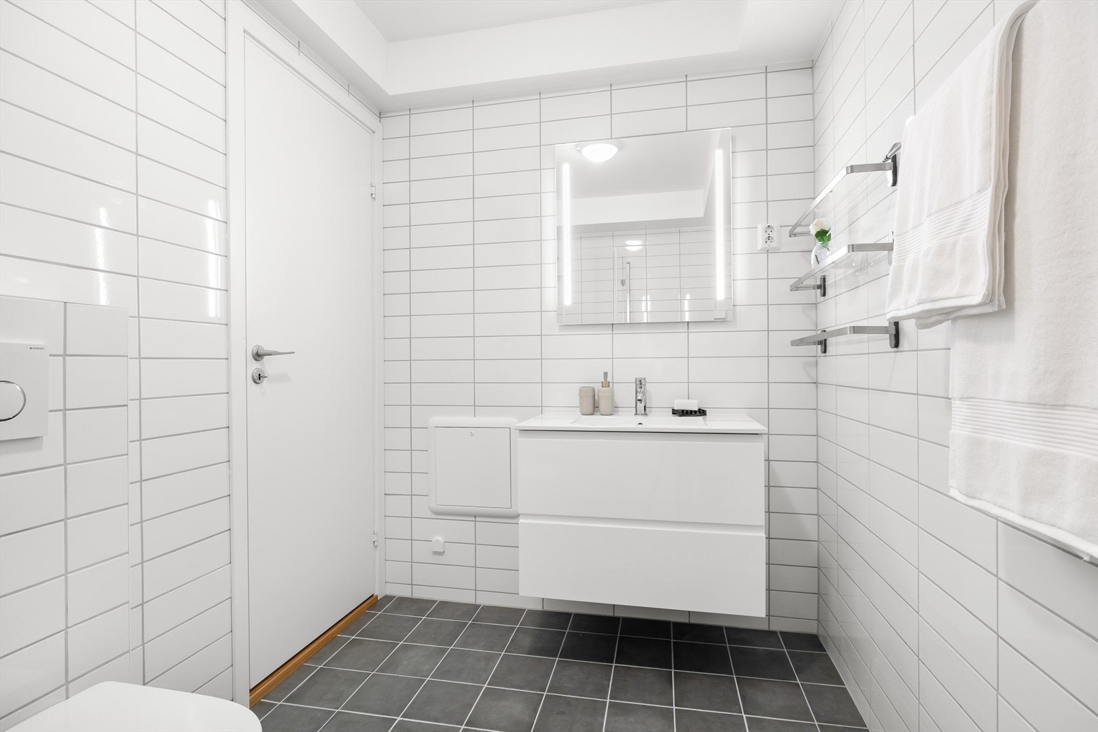 Badet er innredet med vegghengt klosett, servant nedfelt i innredning, speil m/lys og dusjhjørne med svingbare foldedører av glass. Galleribilde