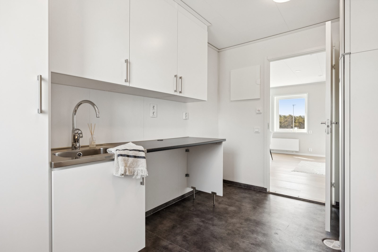 Innenfor kjøkkenet ligger vaskerom/teknisk rom. Her er det utgang ut, så rommet fungerer også som en ypperlig bi-inngang. Praktisk innredning med utslagsvask, benkeplass, god oppbevaringsplass og plass til både vaskemaskin og tørketrommel. Galleribilde