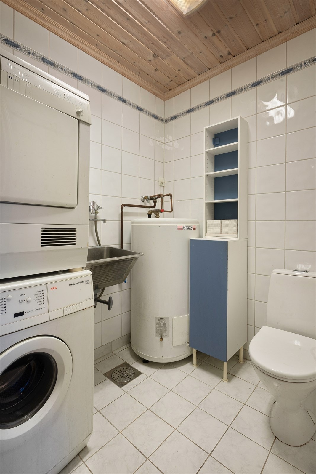 Praktisk separat vaskerom som inneholder toalett, opplegg for vaskemaskin, utslagsvask og varmtvannsbereder Galleribilde