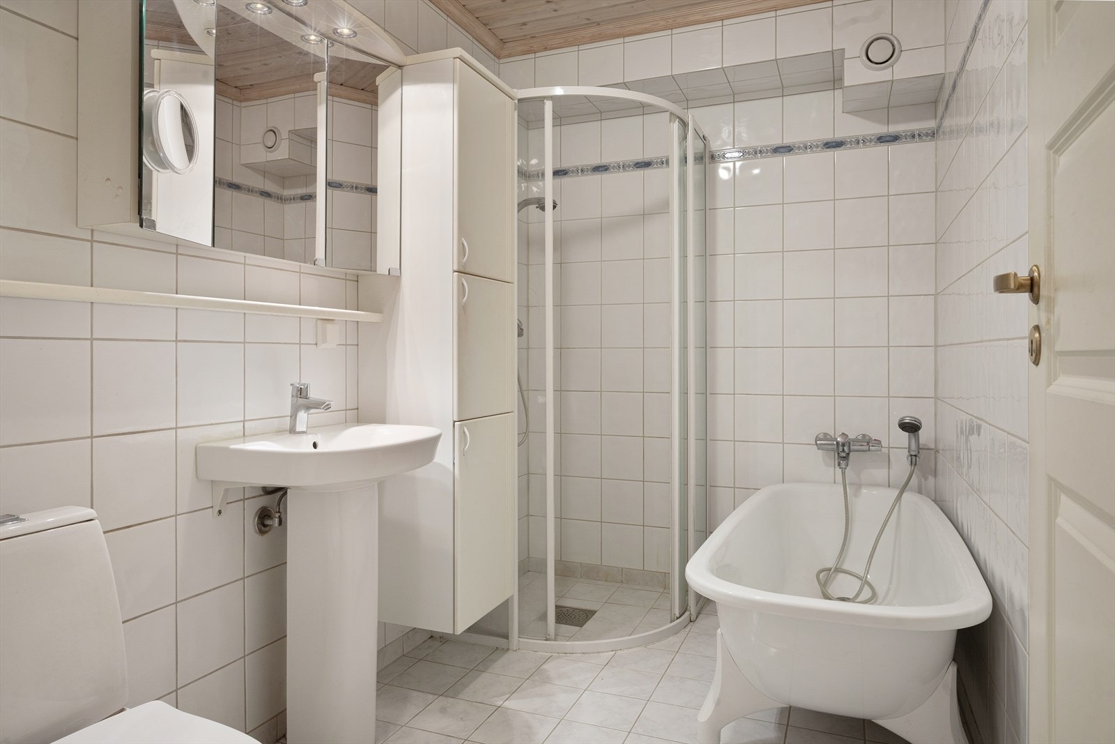 Badet har varmekabler i gulv og inneholder toalett, servant, dusjhjørne og badekar Galleribilde