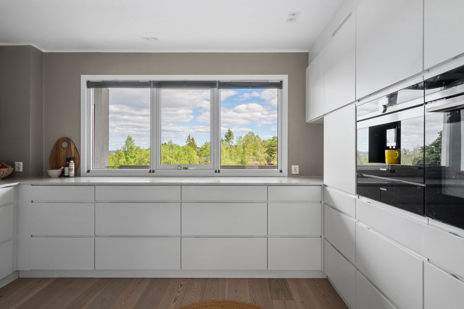 Innredningen er moderne og stilren med hvite, glatte fronter med innfelte håndtak og solid benkeplate i stein. Galleribilde
