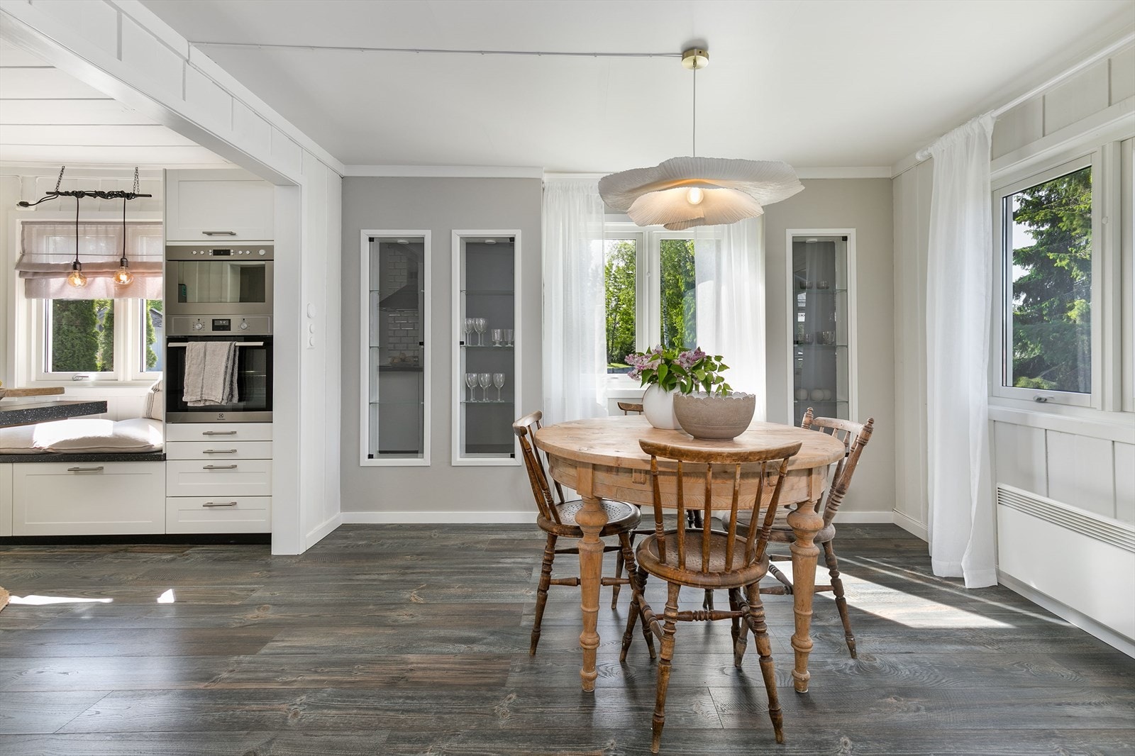 Kjøkkenbord i ytre del av kjøkkenet, med lys inn fra vinduer på flere sider. Galleribilde