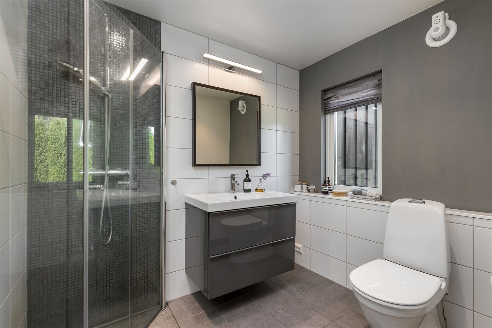 Badet fra 2014 fremstår moderne med flislagte overflater, varmekabler og praktisk dusjhjørne. Galleribilde