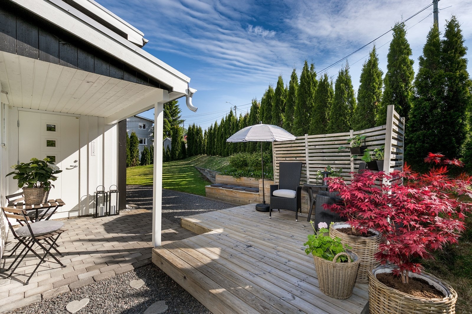 Koselig uteplass ved inngangspartiet, med treplatting og levegg for skjerming. Galleribilde