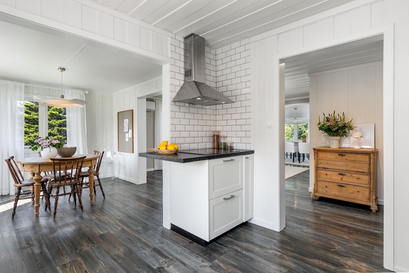 Koketoppen er plassert i et eget hjørne av kjøkkenet med en dekorativ flislagt vegg og fritthengende ventilator. Galleribilde