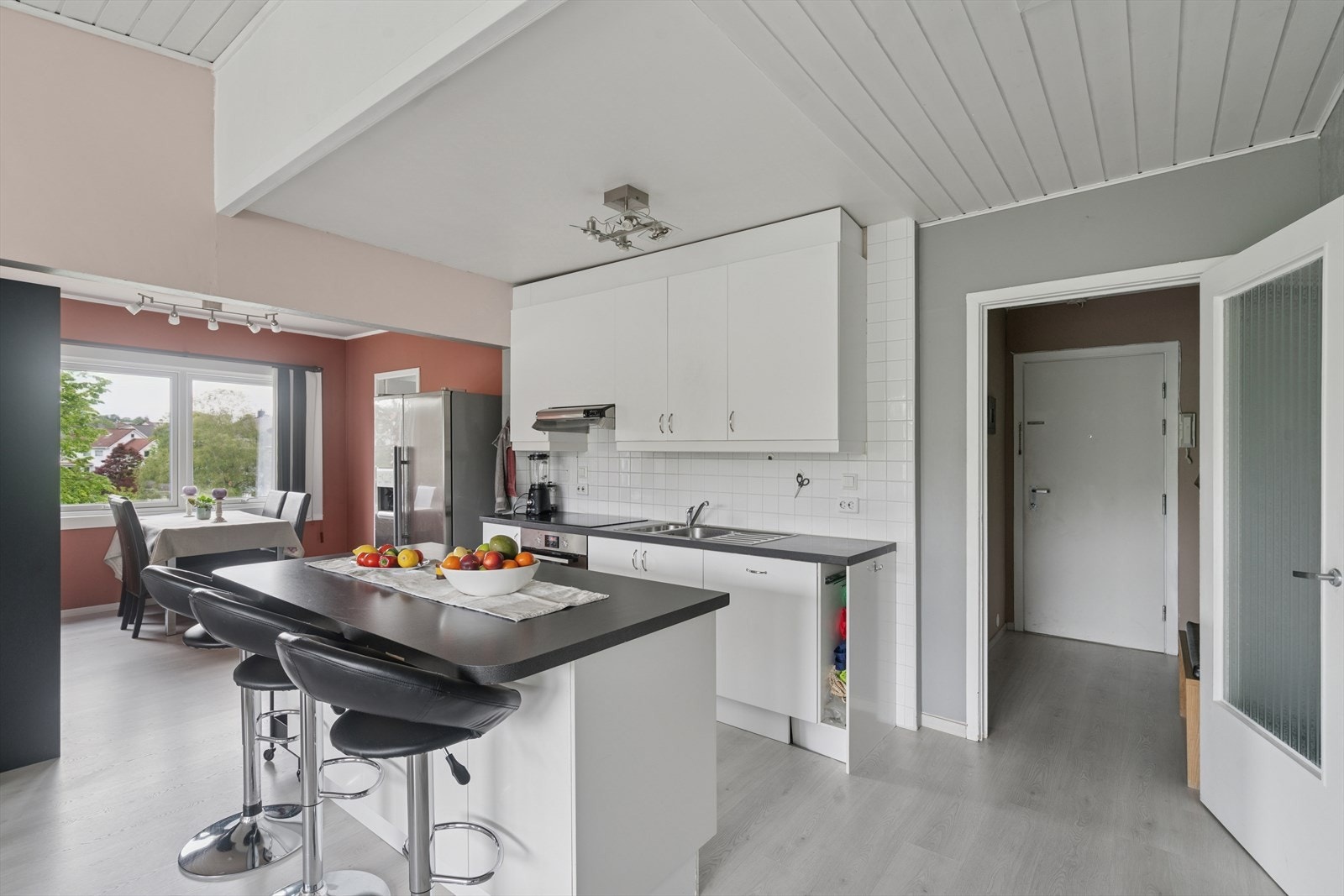 Kjøkkenet fungerer som en romdeler og er innredet med hvite, slette fronter og benkeplate i laminat. Fliser bak kjøkkenbenken gjør det praktisk å holde det rent med mat- og vannsøl. Galleribilde