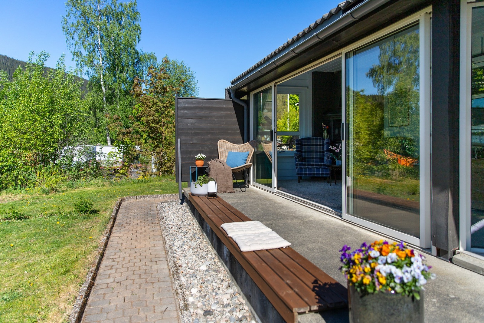 Rullesteineblagte bed, blomsterbed med stauder, bærbusker og hekk er med å sette utrykket på hagen Galleribilde