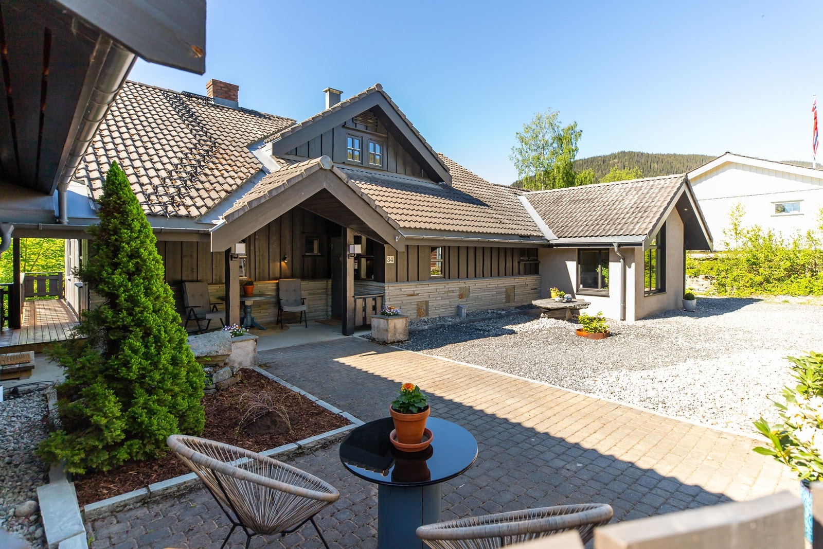 Tomten er pent opparbeidet og byr på en rekke innbydende uteplasser som inviterer til både avslapning og sosiale sammenkomster. Steinbordet blir fjernet før overtagelse Galleribilde