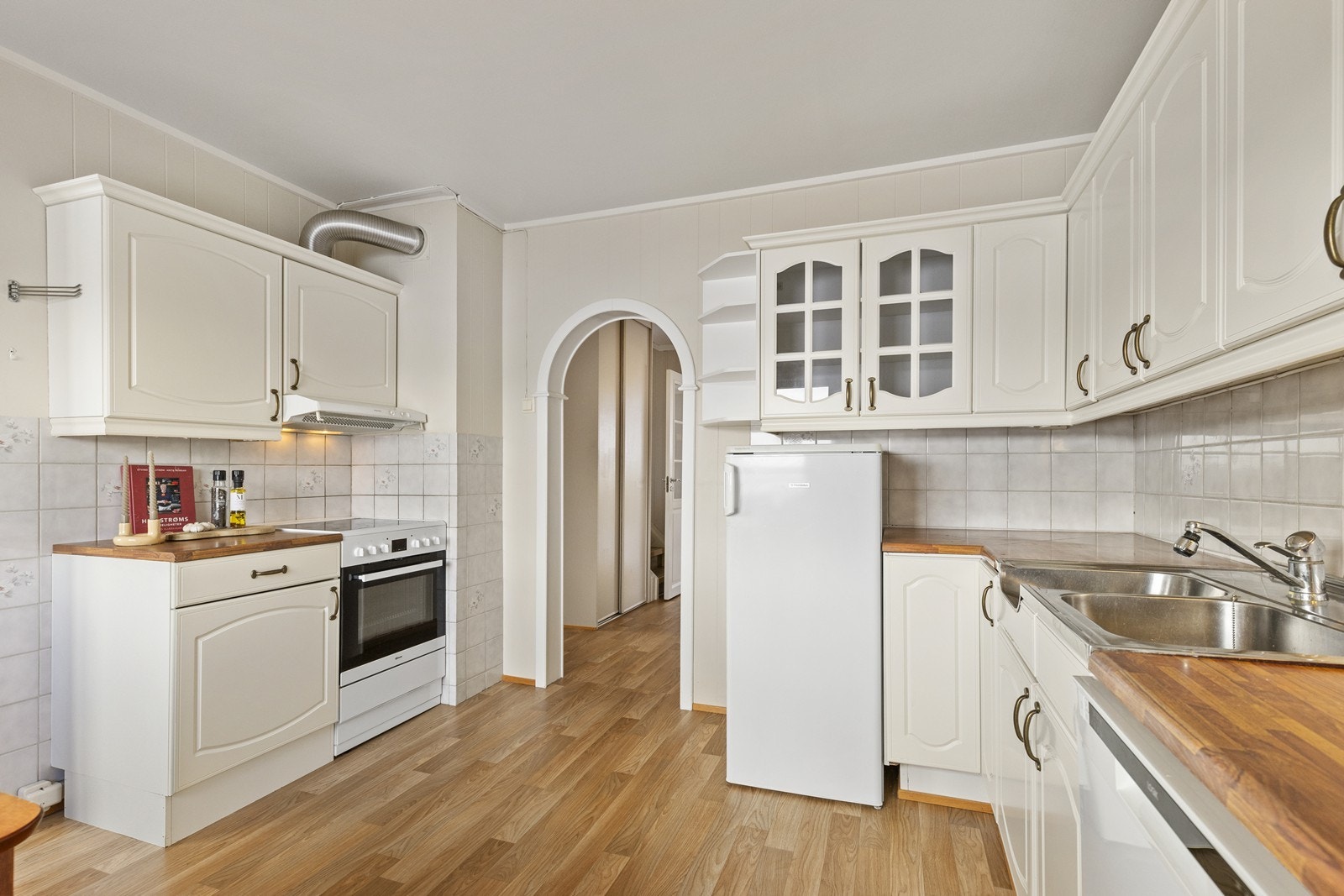 Kjøkkenet har en innredning med profilerte fronter, benkeplate av laminat og fliser på veggen over benkeplaten. Galleribilde