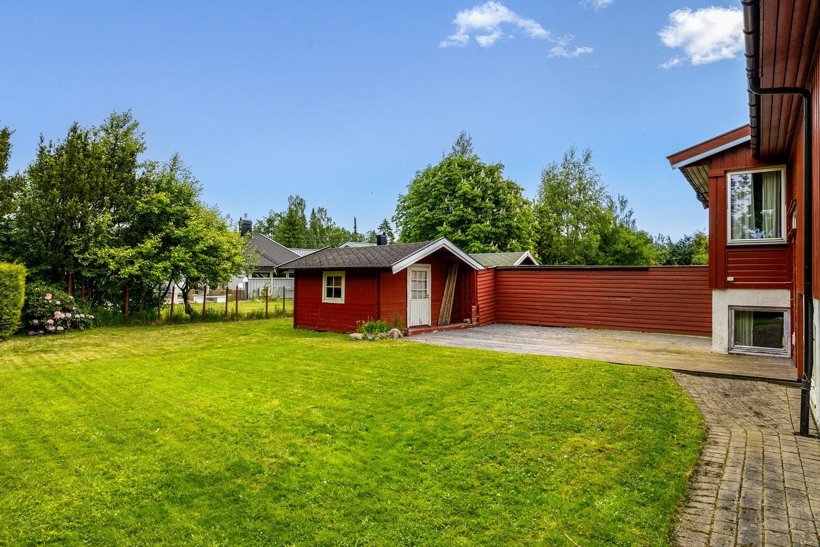 Eiendommen har en stor, pent opparbeidet hage med gressplen og en romslig terrasseplatting - ideell for både barnelek og sosiale sammenkomster i solen. Galleribilde