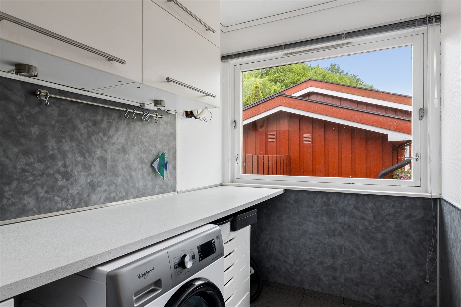 Rommet er utstyrt med benk, skap for oppbevaring, skyllekum og opplegg for vaskemaskin. Galleribilde