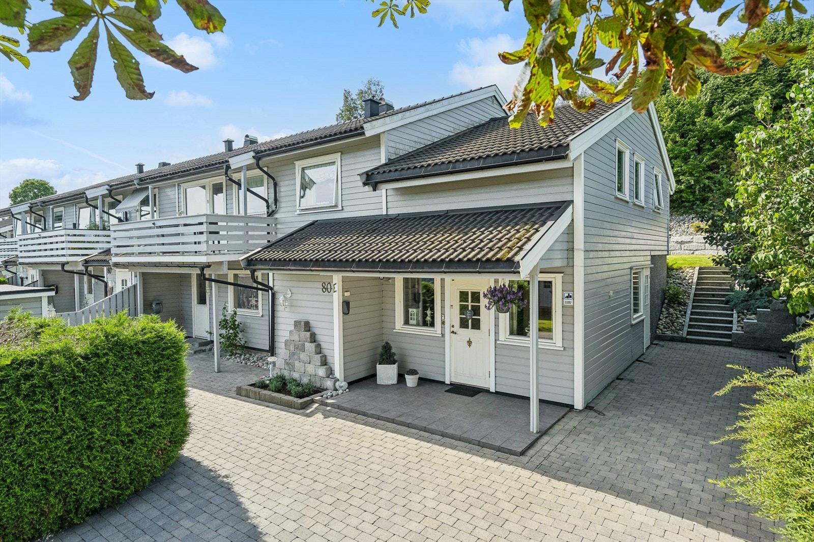 Området rundt denne boligen ble renovert i 2014!
Tomten er opparbeidet med brostein på parkeringsareal. Her er det plass til 2-3 biler på egen gårdsplass.
Fra gårdsplassen er det utvendig skifertrapp opp til usjenert flott hage og terrasse. Galleribilde