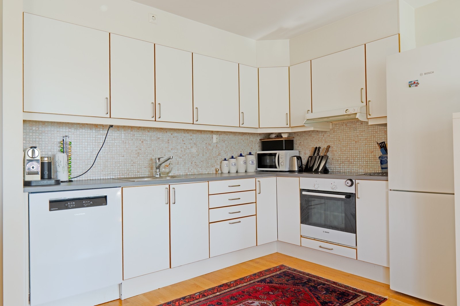 Moderne kjøkken med alt du trenger – inkludert oppvaskmaskin, induksjonstopp, kjøleskap. Galleribilde