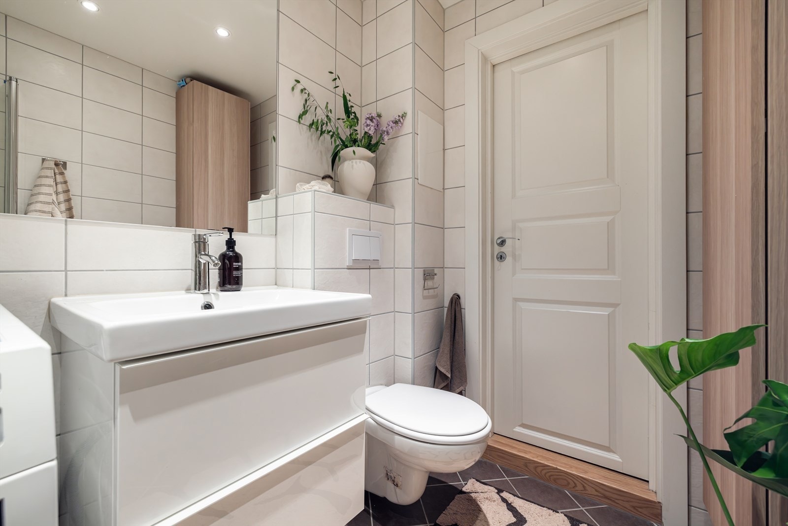 Badet er har gulvvarme og naturlig ventilasjon, og er utstyrt med servant over innredning, sideskap, speil, vegghengt toalett og opplegg for vaskemaskin Galleribilde