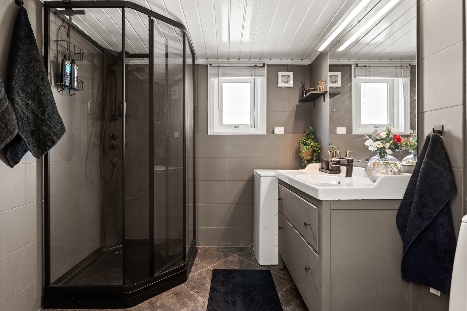 Badet er utstyrt med nedfelt servant, servantskap, gulvfestet toalett, dusjkabinett og høyskap. Galleribilde