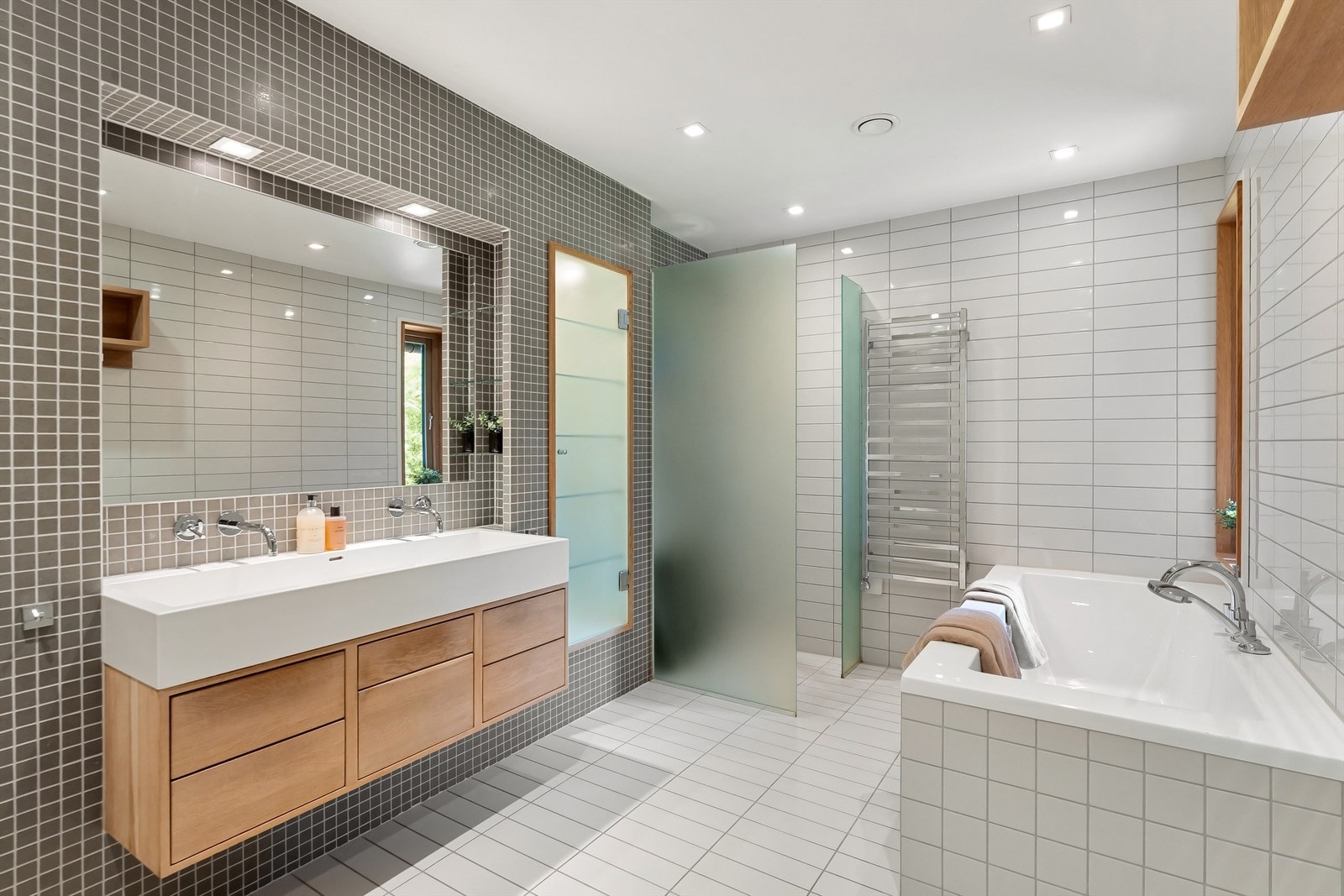 Lekkert baderom med fliser på gulv med gulvvarme, fliser på vegger og nedsenket himling med downlights Galleribilde