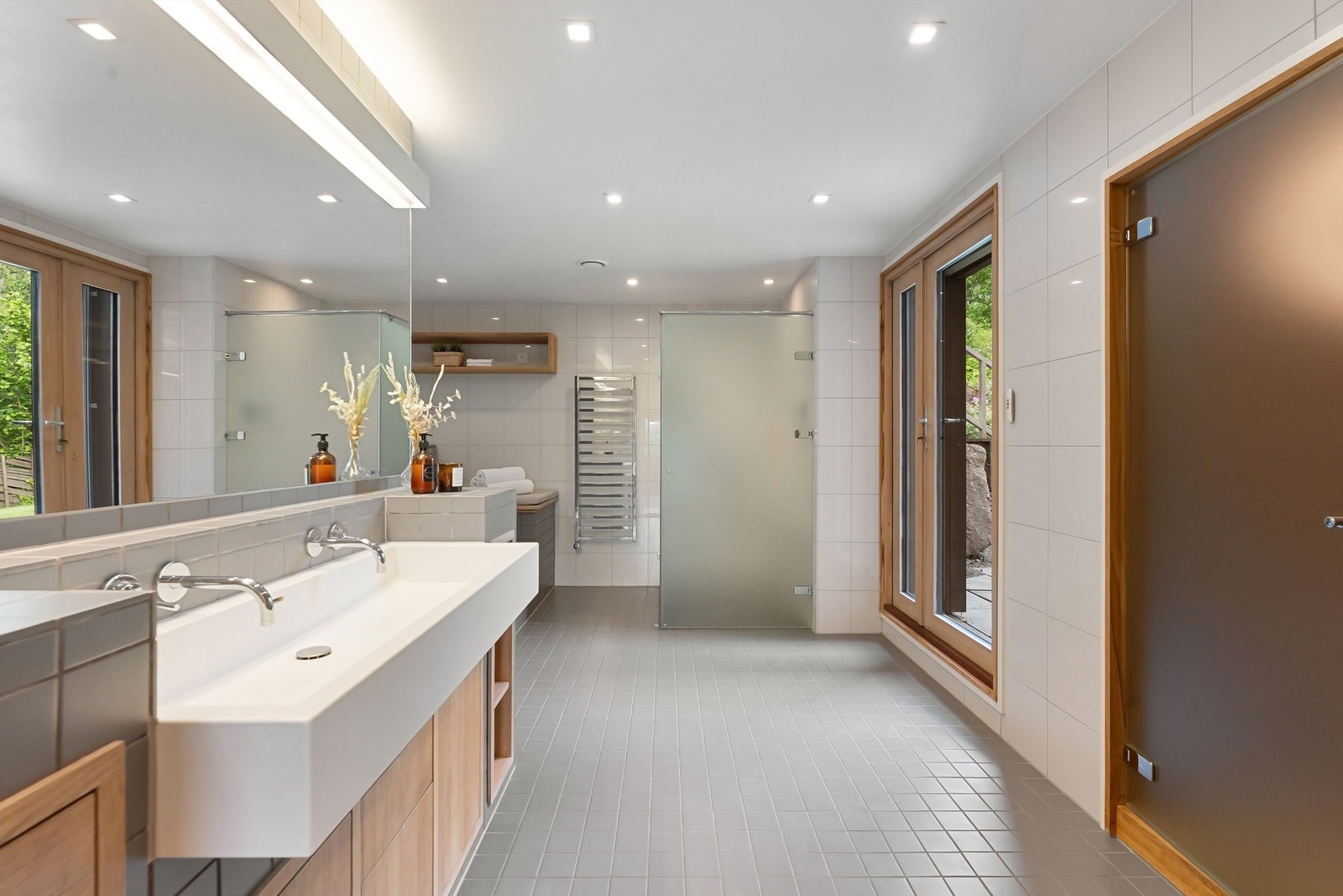 Lekkert baderom med fliser på gulv med gulvvarme, fliser på vegger og nedsenket himling med downlights Galleribilde