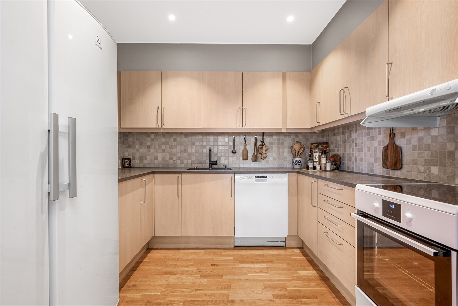 Innredning med opplegg for oppvaskmaskin og mekanisk avtrekksvifte over stekesonen Galleribilde