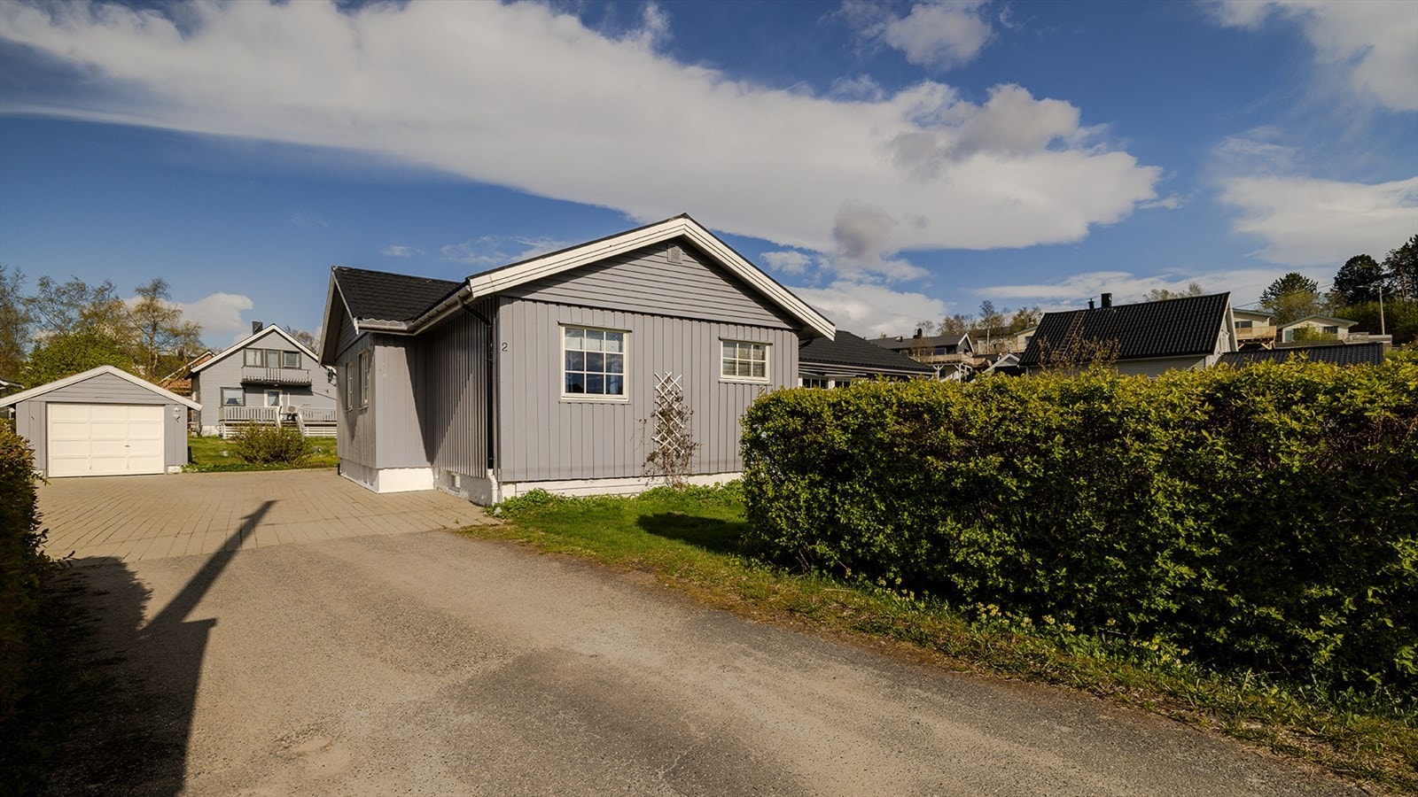 Tomten er opparbeidet med brosteinsbelagt parkeringsområde, plen, hekk, bærbusker, tuntrær, og beplantning. Galleribilde