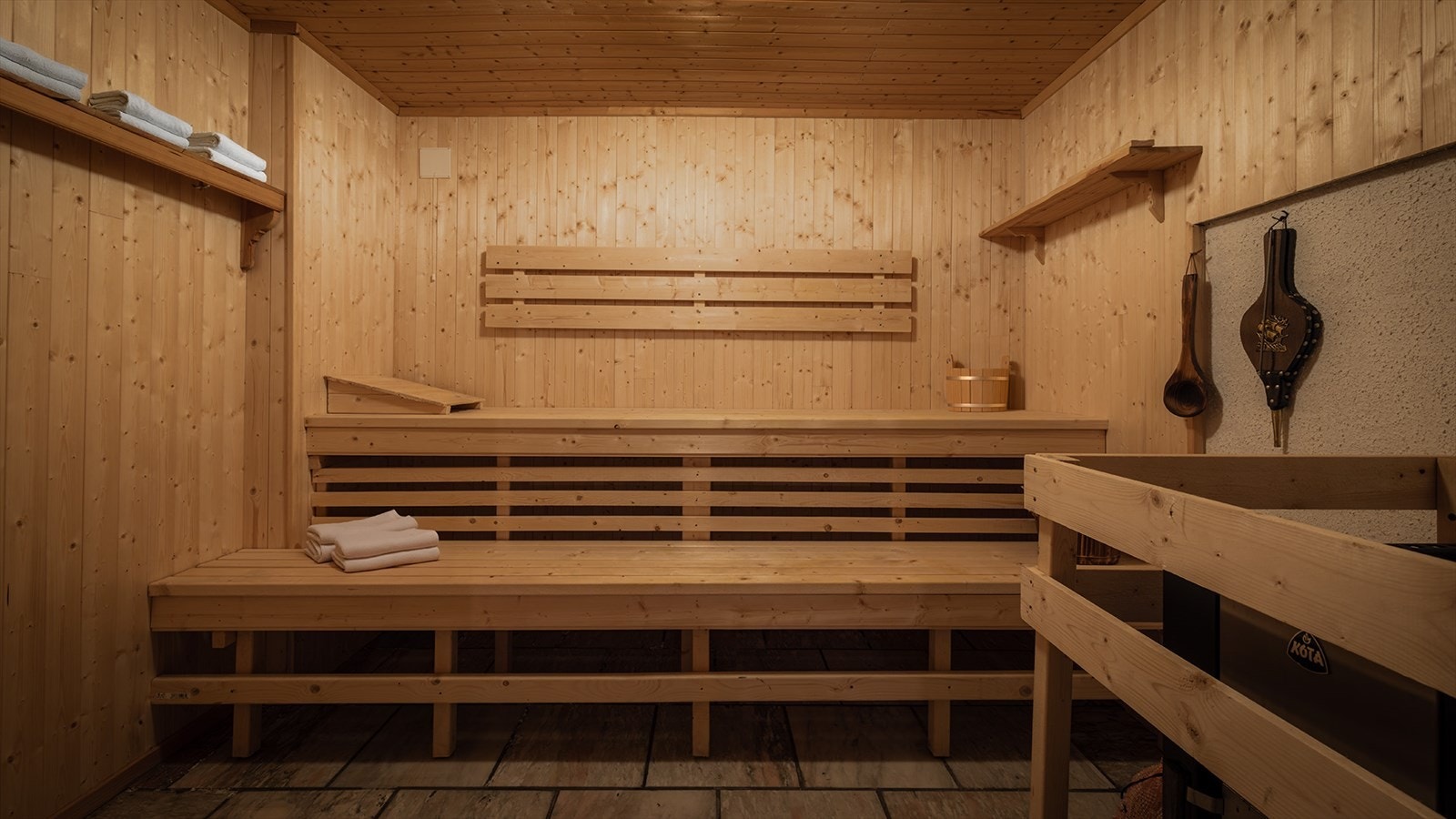 Badstue i kjelleren med marmorflis på gulvet, og trepanel på veggene og i taket. Vedfyrt badstueovn Galleribilde