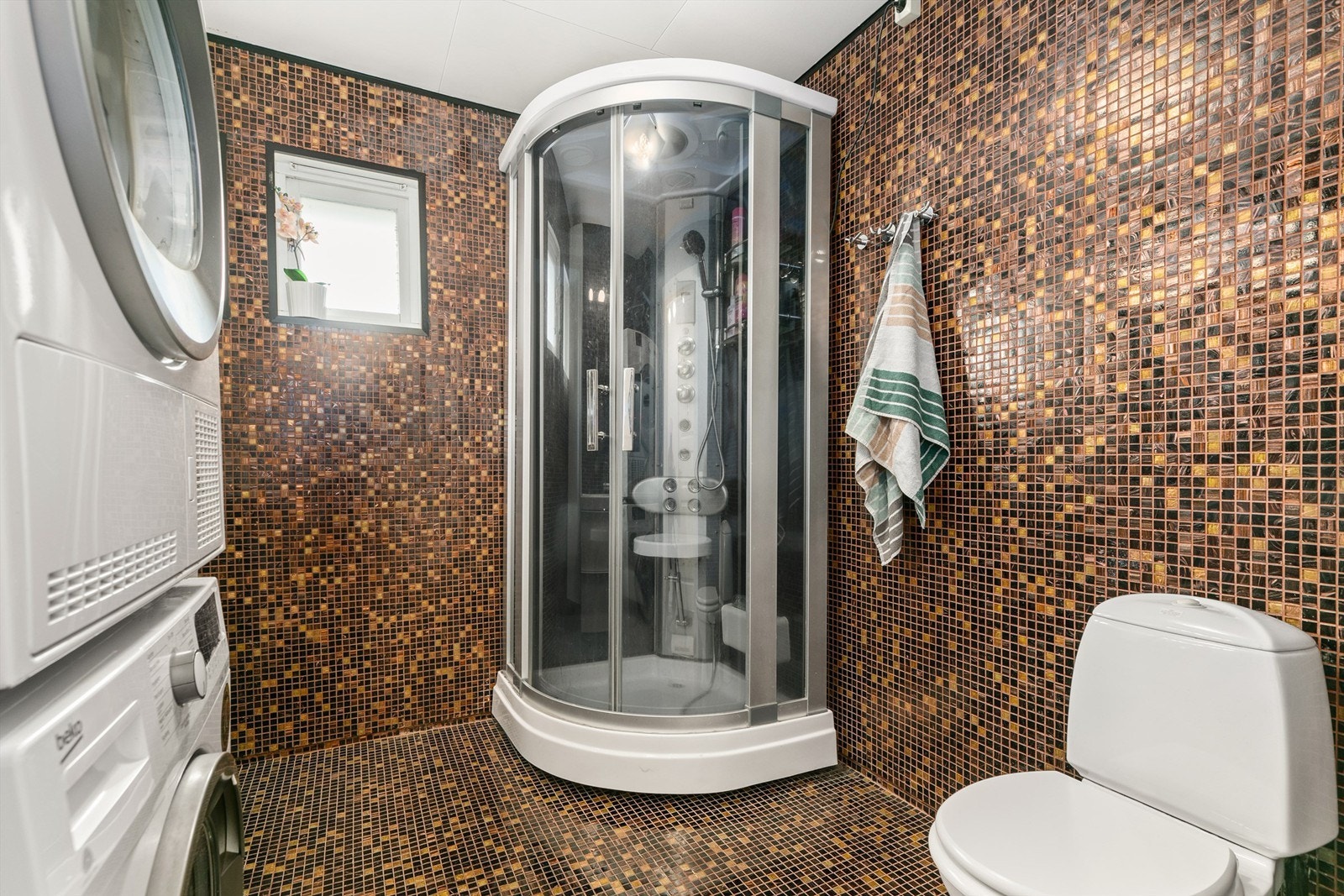 Her er det flislagte gulv med gulvvarme og flislagte vegger. Det er opplegg for vaskemaskin, og både vaskemaskin og tørketrommel kan om ønskelig følge med. Galleribilde
