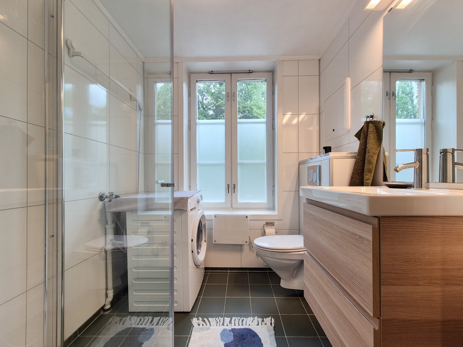 Leiligheten har et pent flislagt baderom med oppbevaring under servant og vaskemaskin. Galleribilde