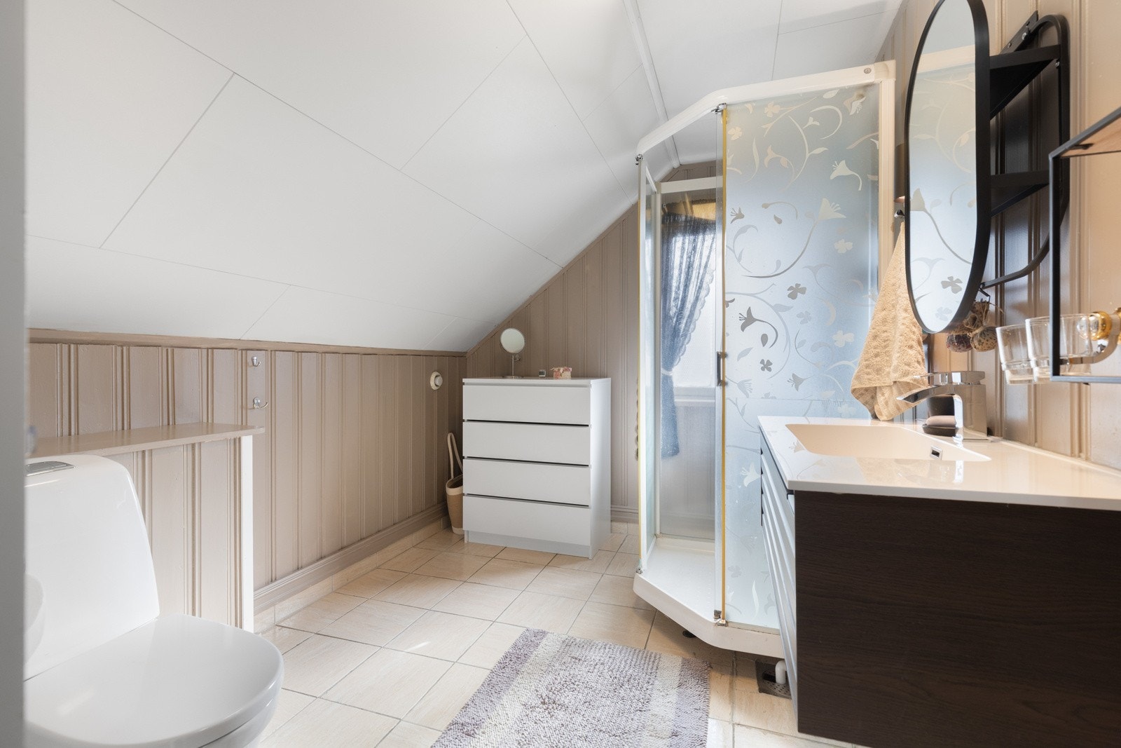 Badet ligger ved soverommene i andre etasje, og har lysmalt panel på veggene og lyse fliser på gulv med gulvvarme. Galleribilde