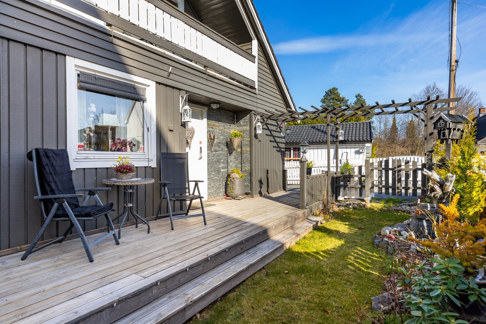 Eneboligen har et pent, inntrukket inngangsparti med asfaltert adkomst, sydvendt velkomstterrasse og veggmontert utebelysning. Galleribilde
