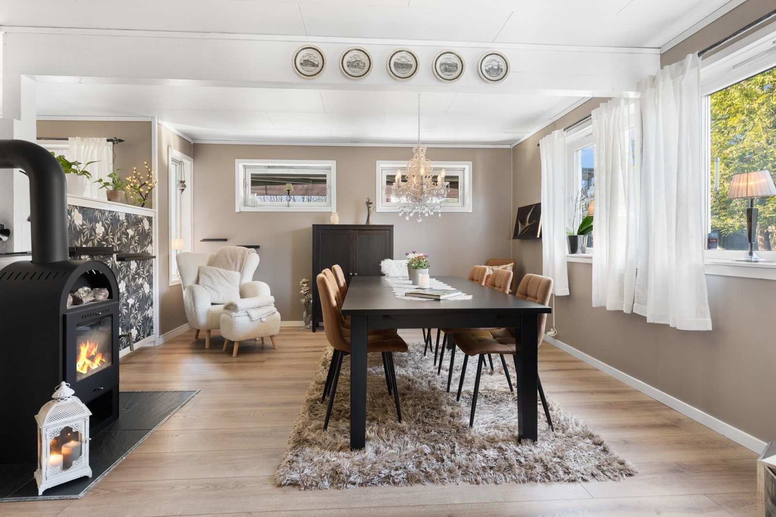Veggene er malt i en dus, gråbeige tone som fremhever det tidsmessige laminatgulvet, og rommet har både varmepumpe og peisovn. Galleribilde