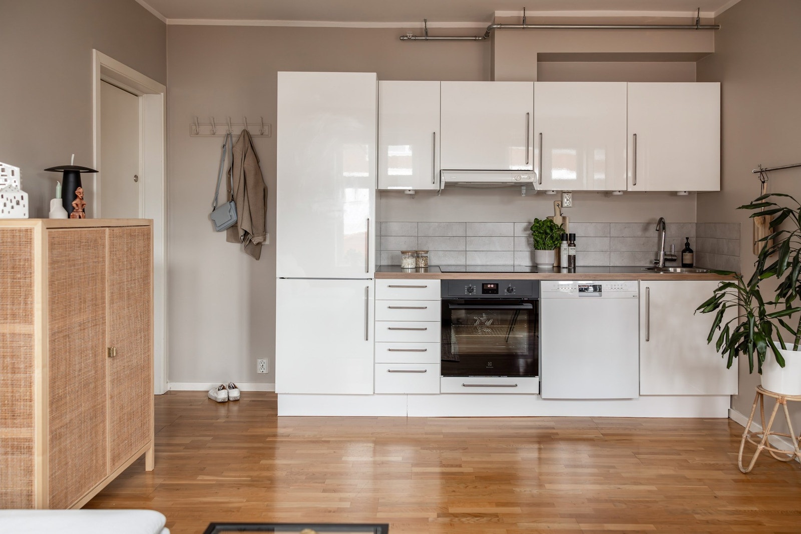 Moderne kjøkkeninnredning med hvite glatte fronter, laminat benkeplate og fliser/belysning mellom over- og underskap. Galleribilde