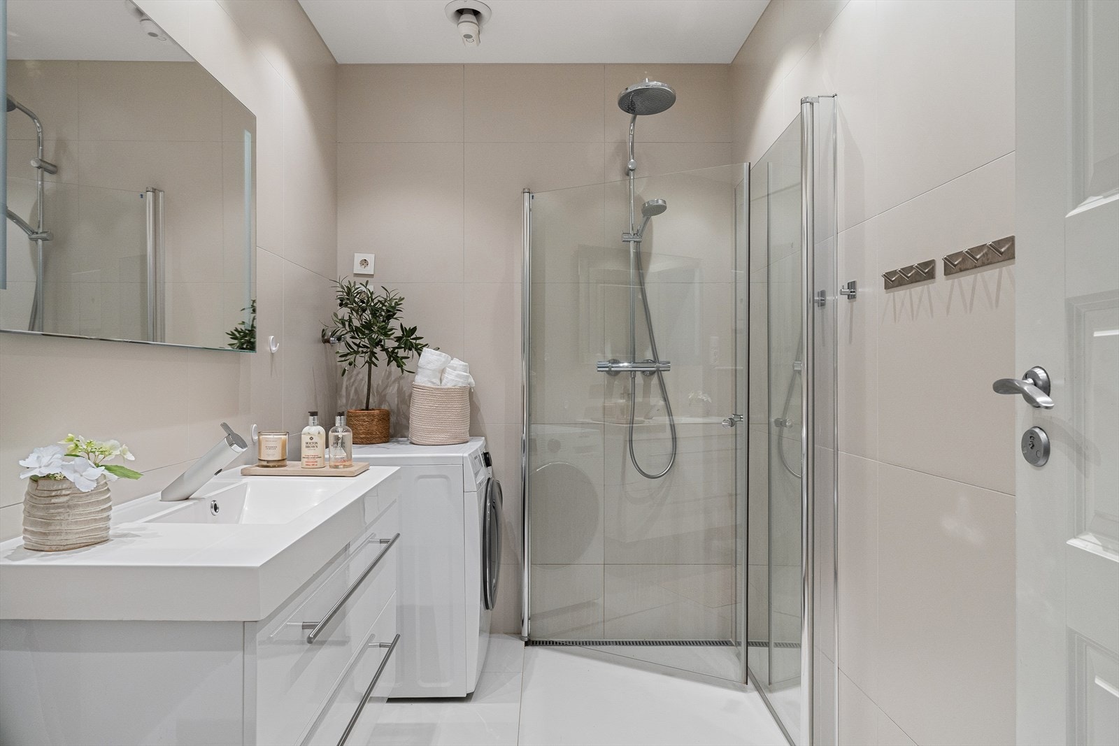 Flotte store fliser på både gulv og vegger, flis i dusjhjørne med vendbare glassdører, vegghengt toalett, opplegg for vaskemaskin, helstøpt vask med underskap og speil overskap. Galleribilde