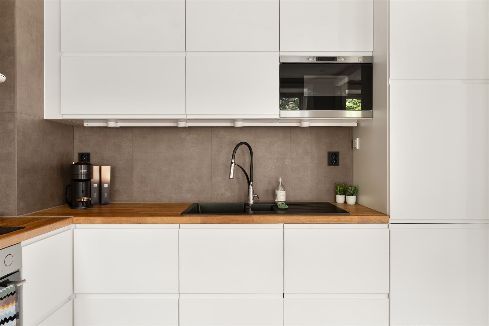 Heltré benkeplate med nedfelt vask med jordfarget fliser over tilfører en varm og naturlig kontrast. Galleribilde