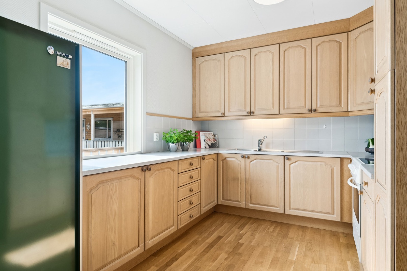 Kjøkkeninnredning med profilerte heltre fronter og benkeplate med vask. Avsatt plass til komfyr og kjøleskap. Galleribilde