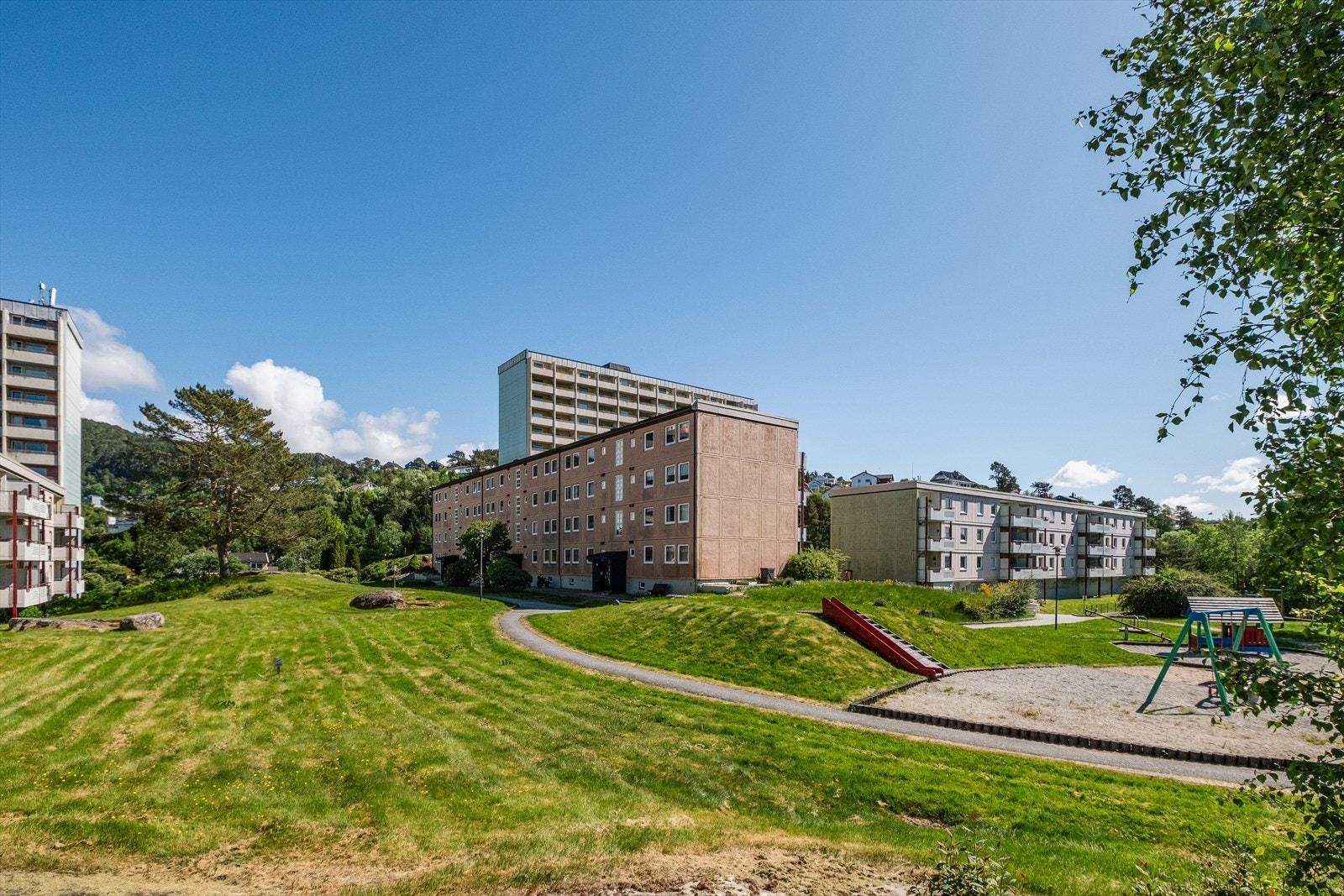 Borettslagets tomt er pent opparbeidet med beplantet fellesareal, plen, lekeplass og interne gangveier. Galleribilde