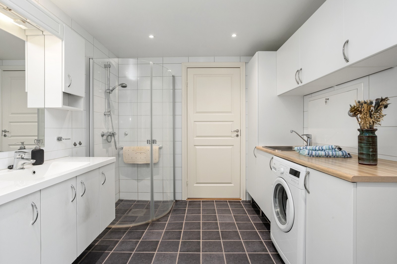 Romslig flislagt bad med dusjhjørne og bod. Galleribilde